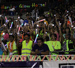 Students on bleachers cheering with glow sticks