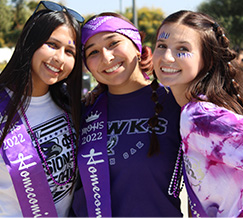 Students smiling and wearing purple sashes