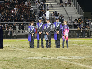 Five marching band members standing on football field